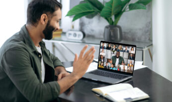 Indian man talking participating in an online discussion using his laptop with a diverse group of people of different races, genders, ages, etc.